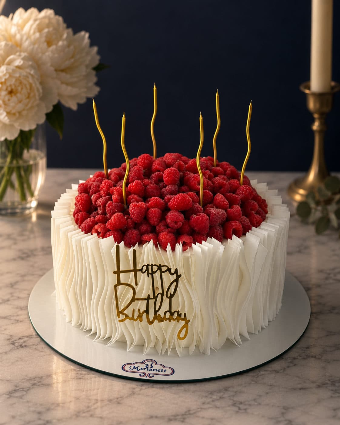 Pastel blanco cubierto de frambuesas con letrero de cumpleaños