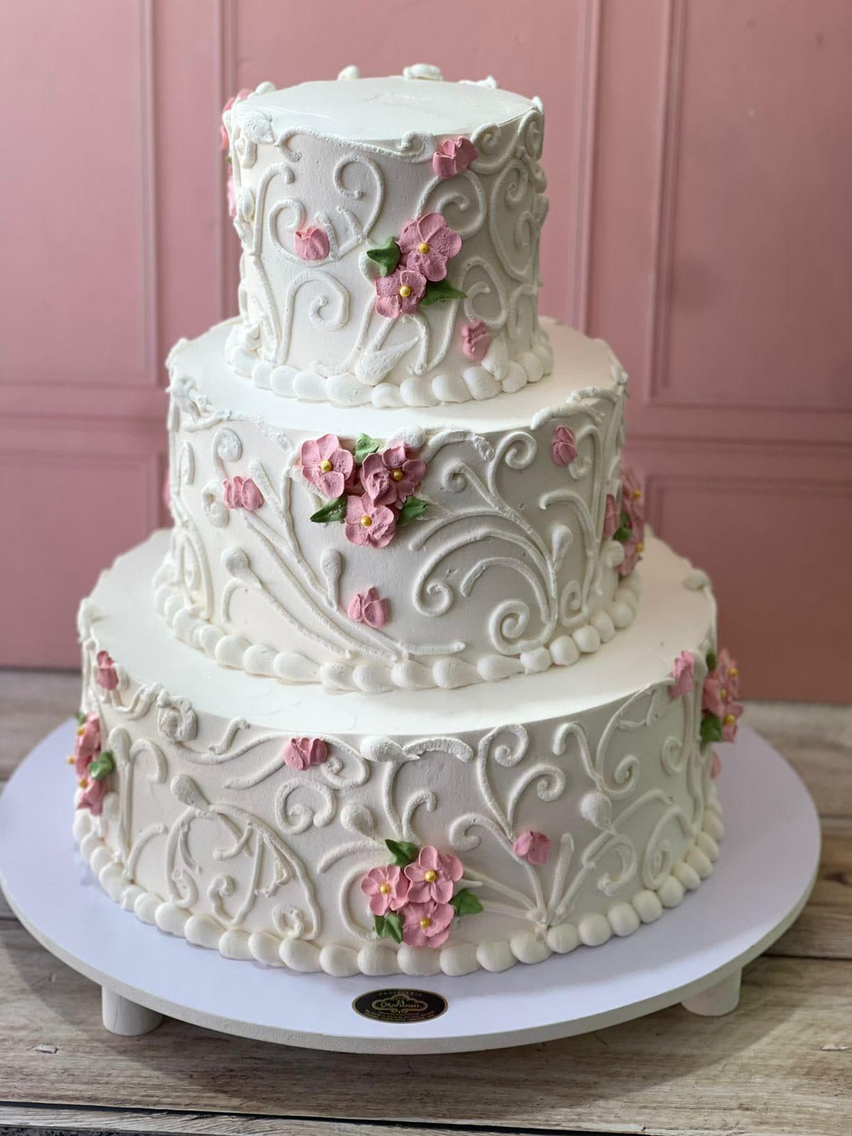 Pastel de tres pisos blanco con flores rosas hechas a mano